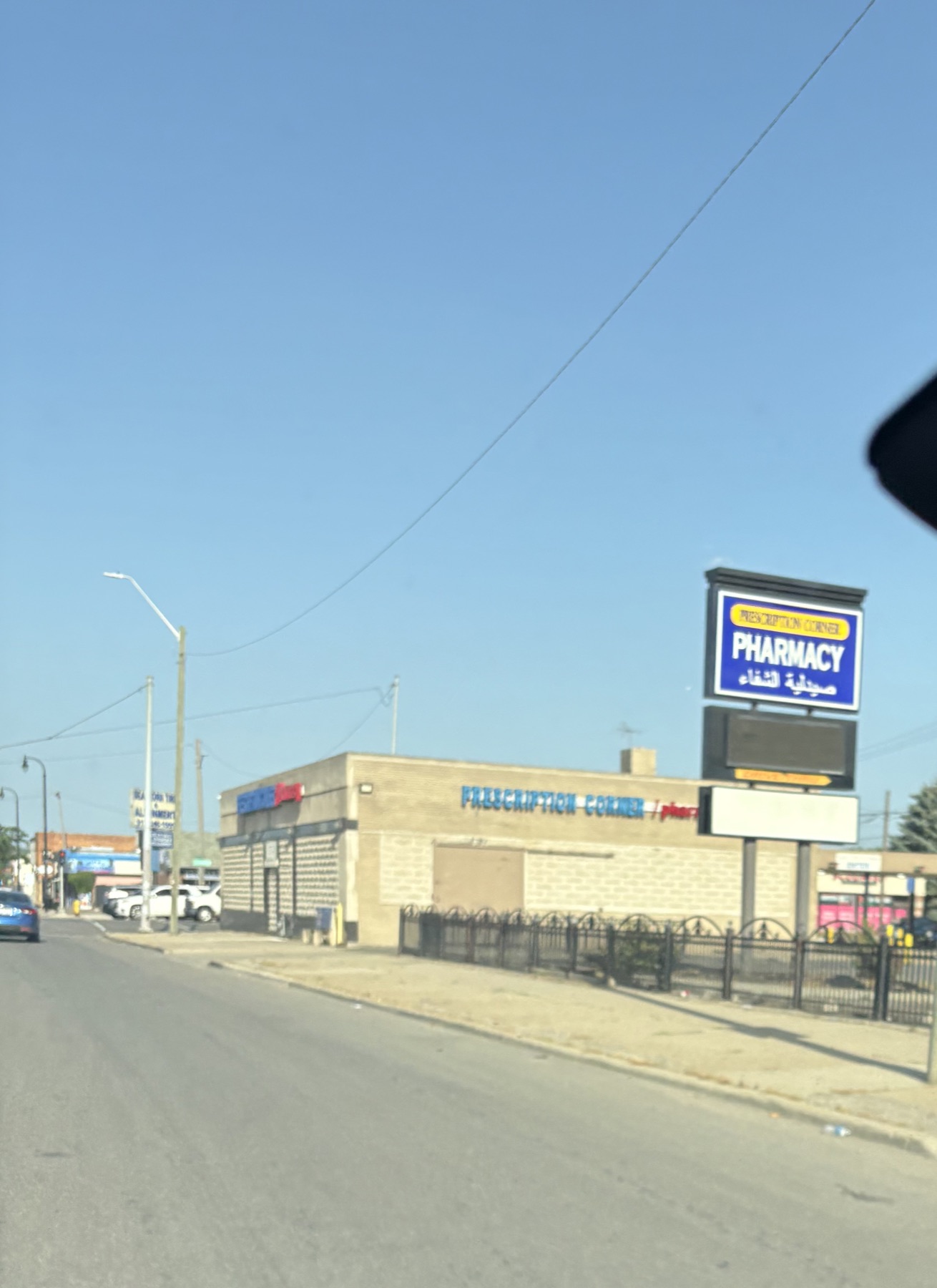 A Dearborn pharmacy with a sign reading PHARMACY in English above Arabic lettering.