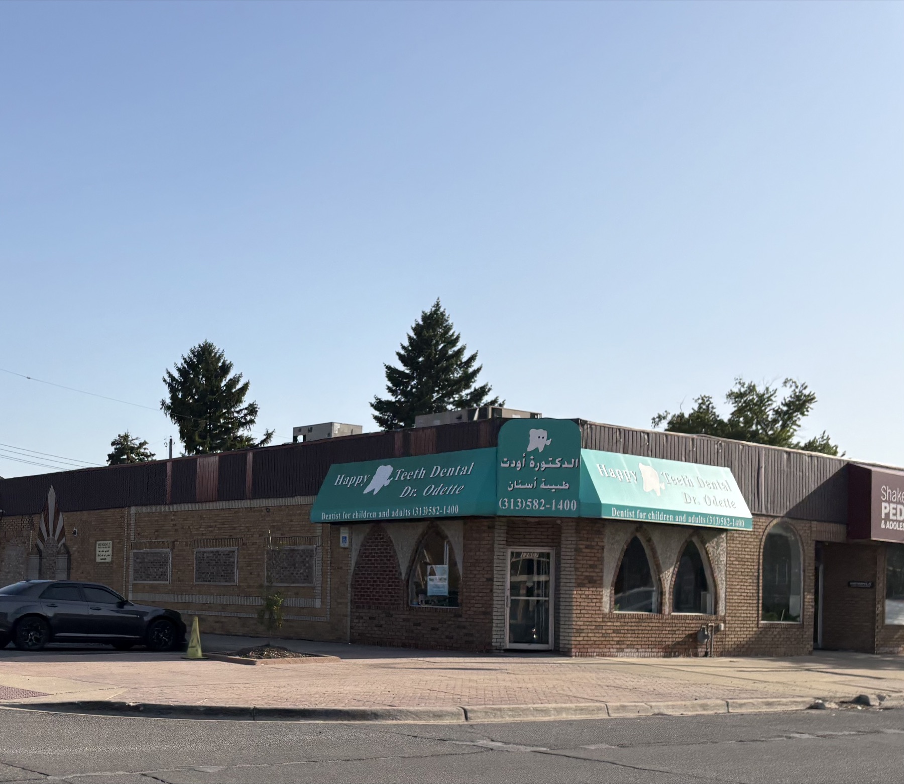 A dental practice in Dearborn signed in English and Arabic, reading Happy Teeth Dental, Dr. Odette, dentist for children and adults.