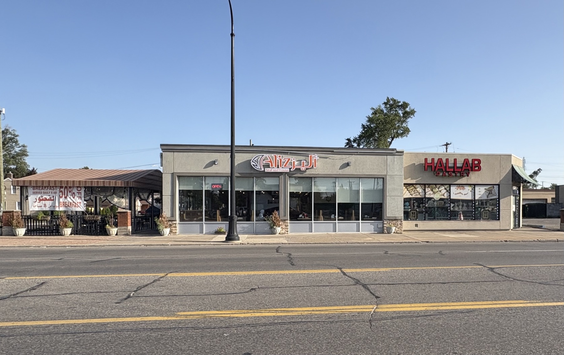 A Dearborn restaurant and a pastry shop side by side, signed Alizz Seafood House and Hallab Pastry.